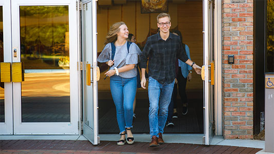 A young women and man exit the University Chapel after a worship service.